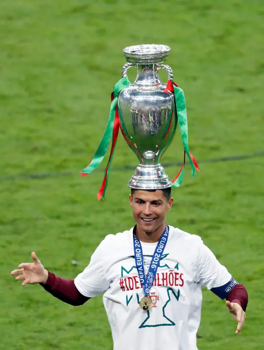 Cristiano Ronaldo bergaya dengan tropi Piala Eropa 2016 usai mengalahkan Prancis 1-0 di Stade de France, Senin (11/7). Ronaldo menjadi pemain yang tampil paling banyak sepanjang perhelatan Piala Eropa berlangsung sebanyak 21 kali. (REUTERS)