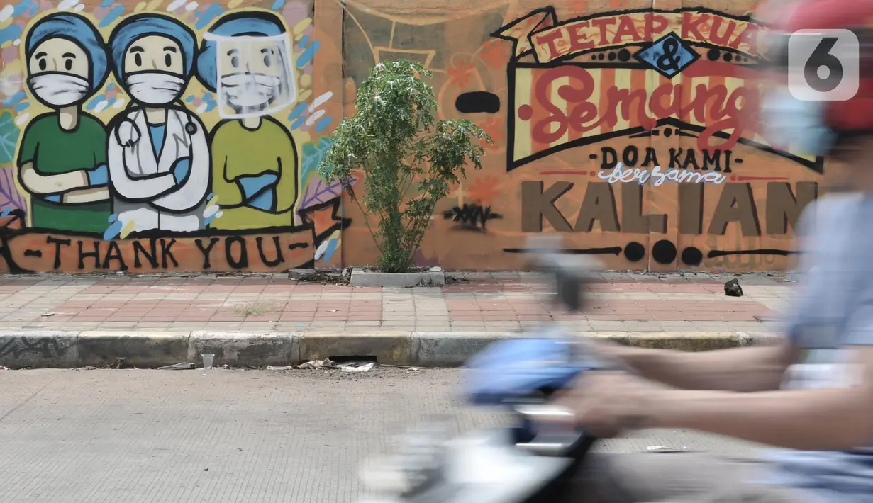 Pengendara melintas di depan mural dukungan untuk tim medis Covid-19 di kawasan Sunter, Jakarta, Rabu (27/5/2020). Mural bergambarkan sosok tim medis dan ungkapan doa ini berada di seberang RS Darurat Wisma Atlet yang dibuat oleh Karang Taruna Kelurahan Sunter Jaya. (merdeka.com/Iqbal S. Nugroho)