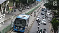 Pengendara motor melaju di belakang bus Transjakarta di kawasan Pasar Rumput, Jakarta, Rabu (20/2). Sekitar 510 CCTV akan dipasang di 225 halte Transjakarta di Ibu Kota untuk menerapkan tilang online atau E-Tilang. (Liputan6.com/Immanuel Antonius)