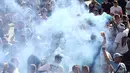 Pendukung Manchester City minum dan bernyanyi di tengah asap biru bom asap di tepi sungai Douro di Porto, Portugal (28/5/2021).  (AP Photo/Luis Vieira)