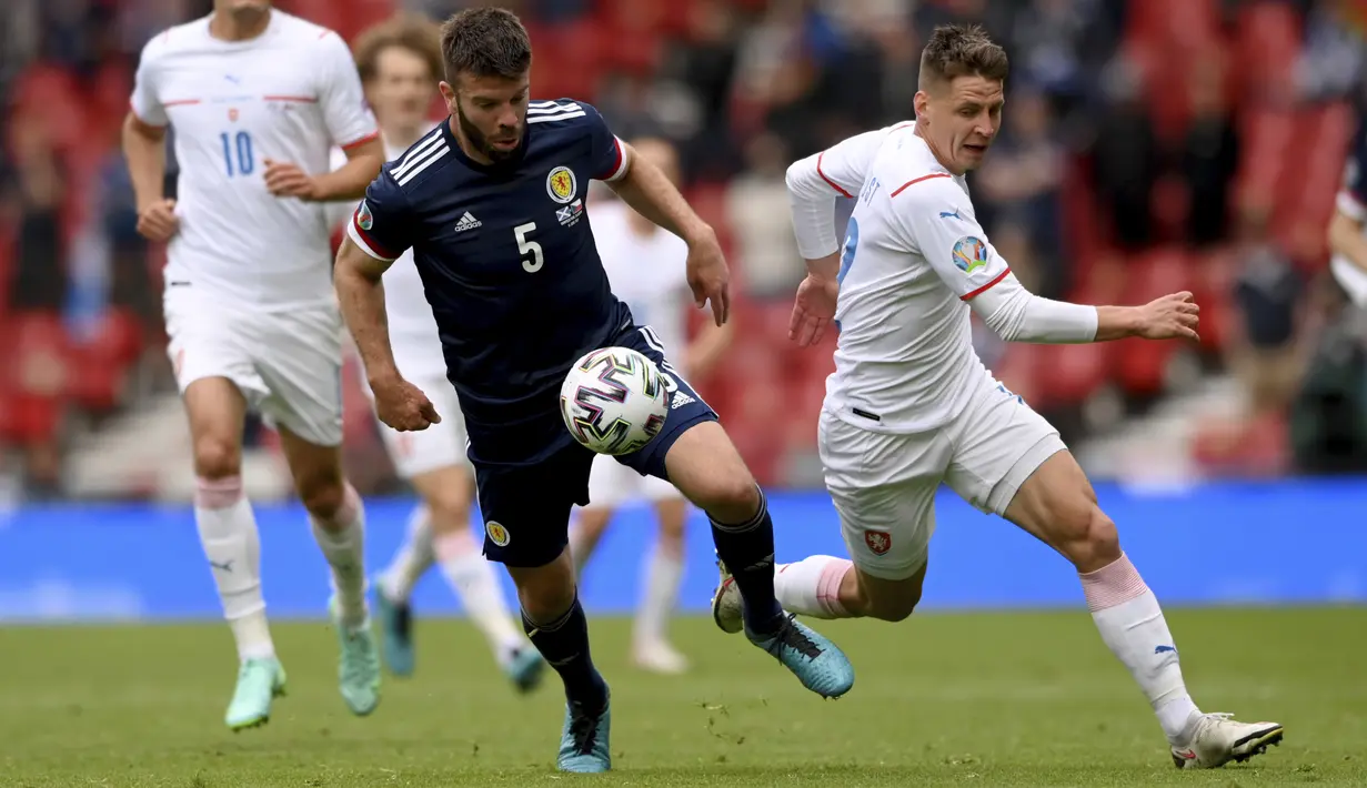Bek Skotlandia, Grant Hanley mengontrol bola dari kejaran pemain Republik Ceko, Lukas Masopust pada pertandingan grup D Euro 2020 di stadion Hampden Park, Glasgow, Senin (14/6/2021). Dengan kemenangan ini, Ceko menggeser Inggris dari puncak klasemen sementara. (Stu Forster, Pool via AP)