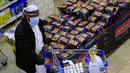 Seorang pria berbelanja bahan makanan dan persediaan saat mereka mempersiapkan diri seminggu menjelang bulan suci Ramadan di supermarket di ibu kota Yaman, Sanaa, Selasa (6/4/2021). (AFP Photo/Mohammed Huwais)