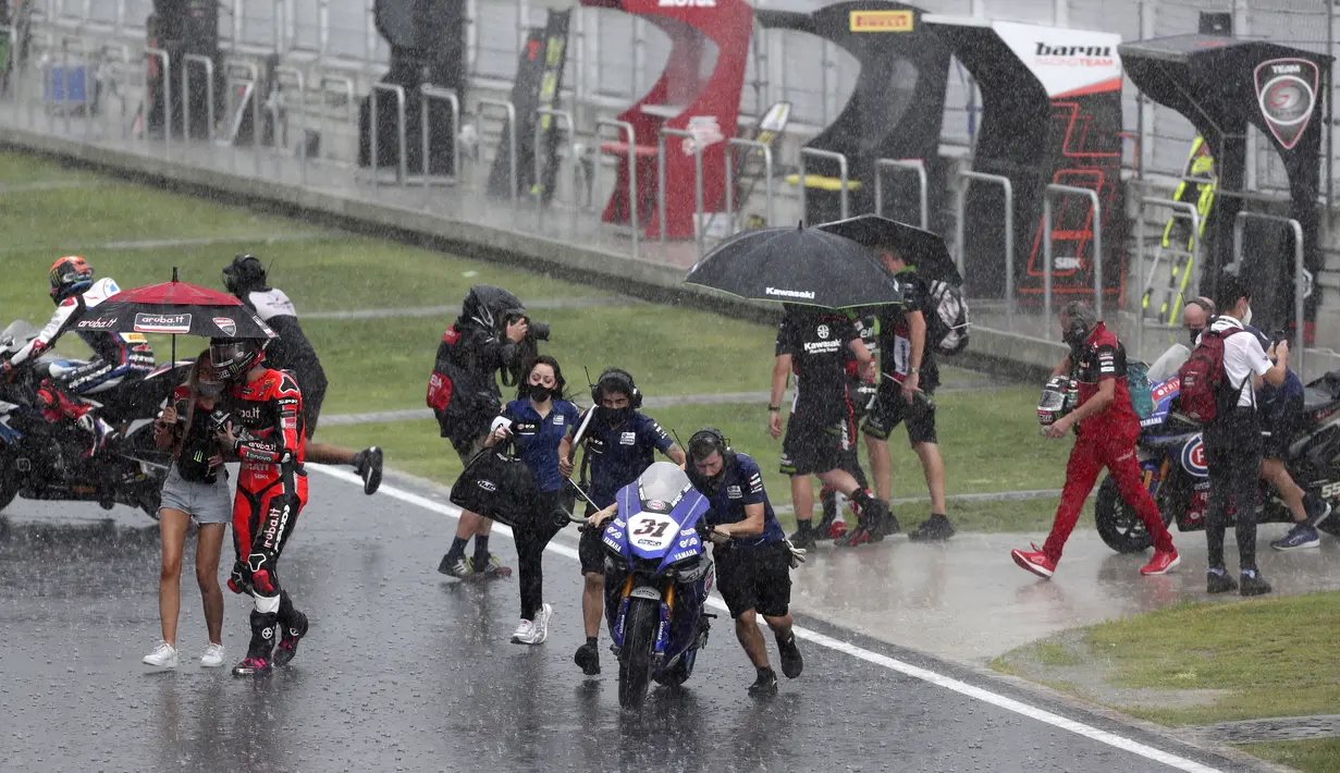 Pembalap dan kru berjalan menuju paddock saat hujan lebat sebelum Race 2 WSBK Mandalika 2021 di Pertamina Mandalika International Street Circuit, Lombok, Nusa Tenggara Barat, Minggu (21/11/2021). Balapan dilanjutkan pukul 15.30 WIB atau 16.30 Wita dan hanya digelar 12 lap. (AP Photo/Achmad Ibrahim)