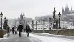 Orang-orang menyeberangi Jembatan Charles abad pertengahan setelah hujan salju pertama di Praha, Republik Ceko (3/12/2020). (AP Photo / Petr David Josek)