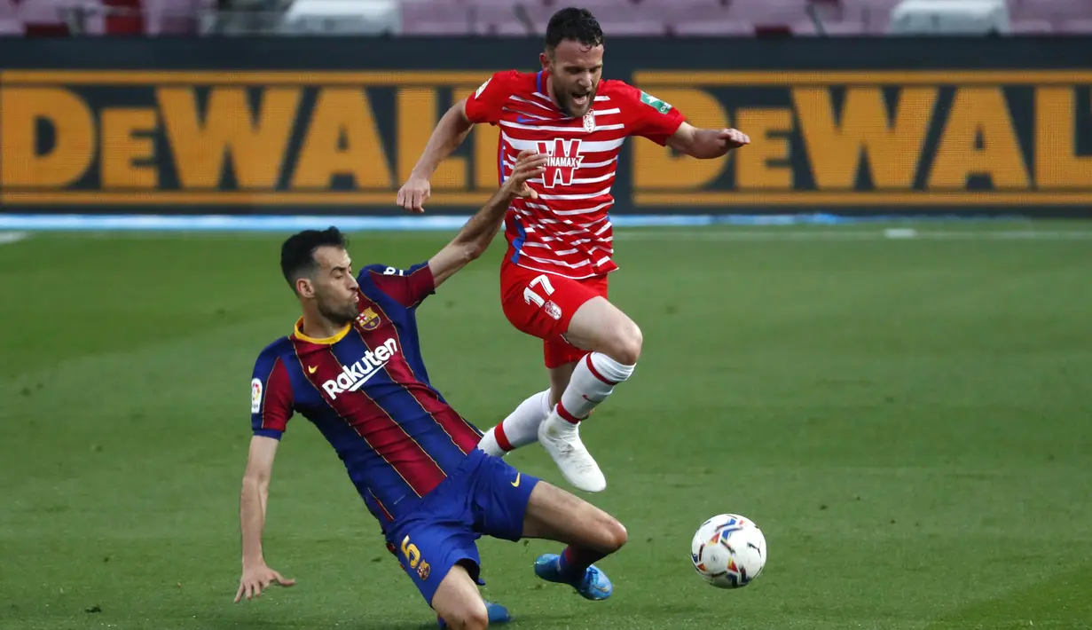 Gelandang Barcelona, Sergio Busquets, berebut bola dengan pemain Granada, Quini, pada laga Liga Spanyol di Stadion Camp Nou, Jumat (30/4/2021). Barcelona takluk dengan skor 1-2. (AP/Joan Monfort)