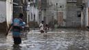 Warga melintasi jalan banjir setelah hujan deras di Karachi, Pakistan, Minggu, (26/7/2020). Sebagian warga memilih untuk bertahan meski rumah mereka terendam banjir. (AP Photo/Fareed Khan)