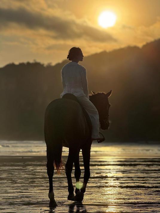 Tak heran jika gaya Pevita Pearce saat menunggang kuda tampil bak kesatria. Pas dengan nuansa matahari terbenam di tepi pantai yang membuat hasil fotonya makin dramatis.  (Liputan6.com/IG/@pevpearce)