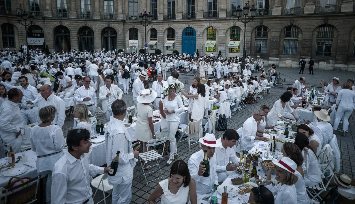 Peserta menikmati makan malam sambil berbincang saat acara 'Diner en blanc' atau 'Makan Malam Putih' di Place Vendome, Paris, Rabu (8/6). Untuk  mendapatkan undangan, peserta harus mengenal seorang anggota organisasi Diner en Blanc. (PHILIPPE LOPE/AFP)