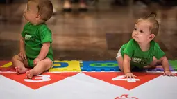 Dua kontestan bayi duduk digaris mulai bersiap mengikuti lomba merangkak dalam Diaper Derby NYC triathlon di New York City (14/7). Menurut penonton, aksi para bayi ini menggemaskan dan menghibur mereka. (AFP Photo/Dominick Reuter)