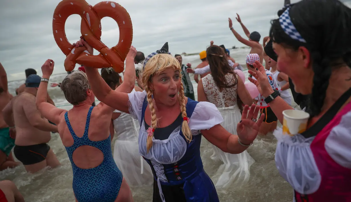 Orang-orang dengan mengenakan kostum warna-warni menyerbu perairan Laut Utara  untuk merayakan akhir pekan pertama Januari 2020 di Ostend, Belgia, Sabtu (4/1/2020). Cuaca dingin tak menghalangi mereka untuk menceburkan diri ke laut yang merupakan salah satu tradisi tahun baru.  (AP/Francisco Seco)