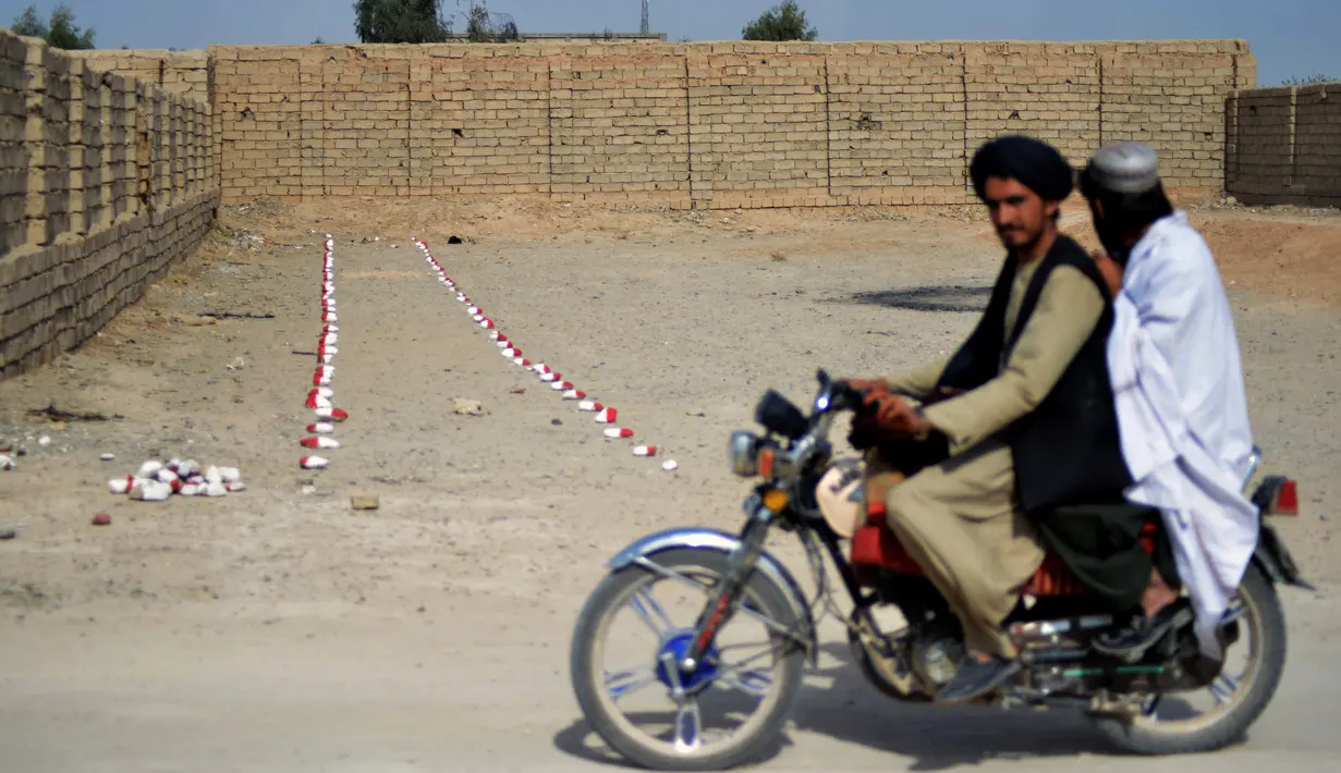 Warga berkendara melewati ladang ranjau di desa Nad-e-Ali, provinsi Helmand pada 9 November 2021. Sekitar 41.000 warga sipil Afghanistan terbunuh atau terluka oleh ranjau darat dan persenjataan yang tidak meledak sejak 1988, menurut Layanan Pekerjaan Ranjau PBB (UNMAS). (Javed TANVEER/AFP)