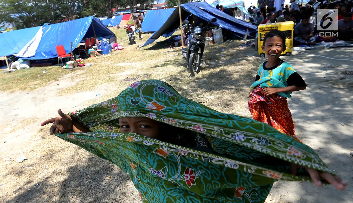 Anak-anak pengungsi korban gempa dan tsunami Palu berjalan di lapangan Masjid Agung Daru Salam, Palu, Sulawesi Tengah, Jumat (5/10). Pemerintah tengah menentukan lokasi yang tepat untuk membangun hunian sementara bagi korban. (Liputan6.com/Fery Pradolo)