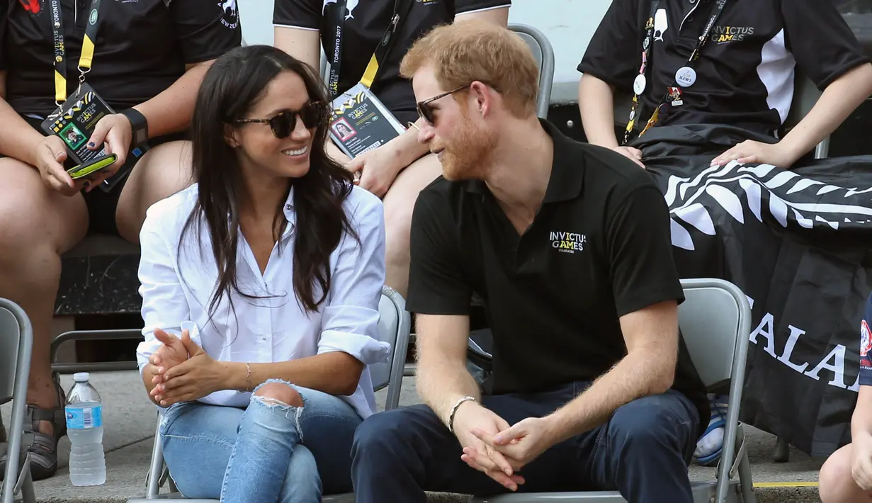 Pangeran Harry dan kekasihnya Meghan Markle menonton pertandingan tenis kursi roda selama Invictus Games 2017 di Toronto, Kanada, Senin (25/9). Selama pertandingan, keduanya tampak akrab, sambil sesekali berbisik satu sama lain. (AP Photo)