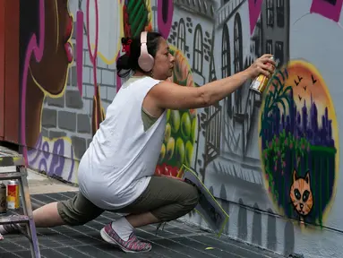 Seniman grafiti Sandra Fabara atau lebih dikenal Lady Pink melukis mural di Casita Maria, Bronx, New York, AS, Minggu (2/6/2019). Lady Pink dikenal juga dengan julukan 'The First Lady of Graffiti' atau 'Ibu Negara Grafiti'. (Don Emmert/AFP)