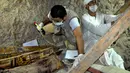 Arkeolog Mesir meneliti peti mati kayu yang ditemukan di sebuah pemakaman berumur 3.500 tahun, sebelah selatan kota Luxor, Selasa (18/4). Dari makam itu ditemukan setidaknya delapan mumi, yang diduga anggota dari keluarga hakim. (STRINGER/AFP)