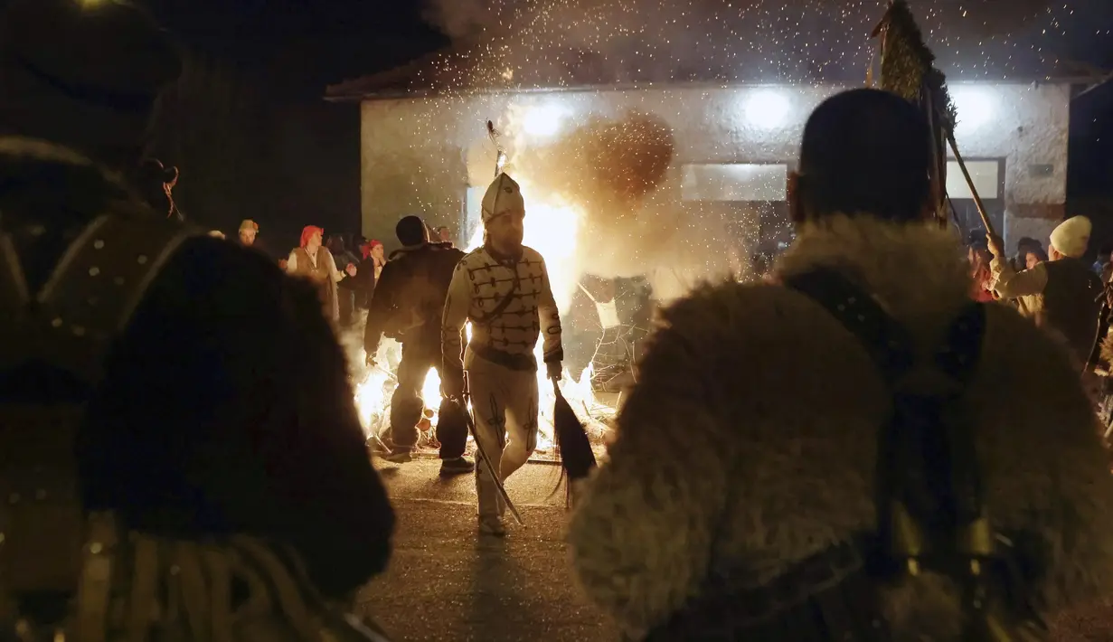 Para penari melakukan ritual kuno di sekitar api unggun mengusir roh-roh jahat di jalan-jalan Batanovci, Bulgaria, Kamis (13/1/2022). Untuk dua tahun ini festival topeng memiliki arti ekstra: orang-orang berharap itu akan membawa kelegaan dari kesengsaraan pandemi corona. (AP/Valentina Petrova)