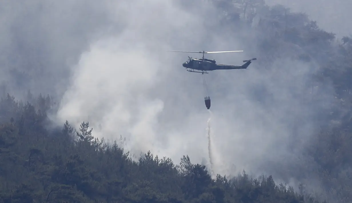 Helikopter tentara Lebanon menjatuhkan air di atas kebakaran hutan, di desa Qobayat, Lebanon, Kamis (29/7/2021). Petugas pemadam kebakaran Lebanon berjuang di hari kedua untuk mengatasi kebakaran hutan di utara negara itu yang telah menyebar ke seluruh perbatasan ke Suriah. (AP Photo/Hussein Malla)