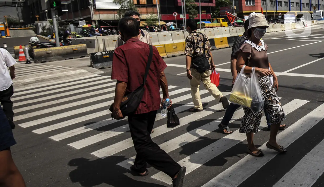 Warga menyeberang jalan menggunakan pelican crossing di kawasan Glodok, Jakarta, Sabtu (22/1/2022). Halte Glodok baru merupakan halte lama yang terdampak proyek pembangunan MRT Fase II. (Liputan6.com/Johan Tallo)