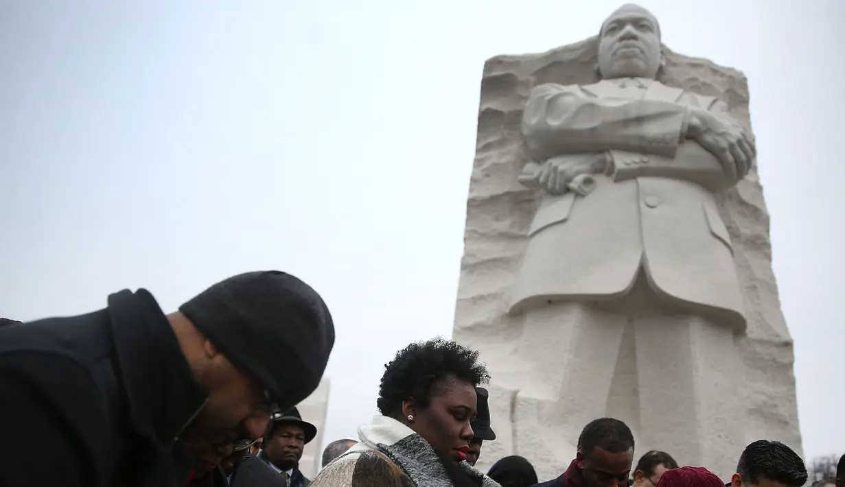 Sejumlah orang berkumpul dan berdoa di depan Patung Martin Luther King Jr, Washington DC, AS, Senin (16/1). Di Amerika Serikat, Senin pada Minggu ketiga diperingati sebagai 'Hari Martin Luther King Jr'. (Joe Raedle / Getty Images / AFP)