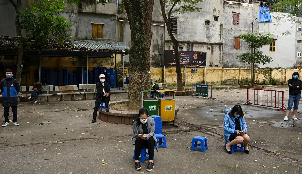 Penduduk memakai masker mengantre dengan tertib saat akan mengikuti pengujian Covid-19 di pusat pengujian dekat rumah sakit Bach Ma, Hanoi, Vietnam (31/3/2020). Warga Vietnam antusias mengikuti tes Covid-19 dengan tertib di tengah masifnya penyebaran Covid-19 di dunia. (AFP/Manan Vatsyayana)