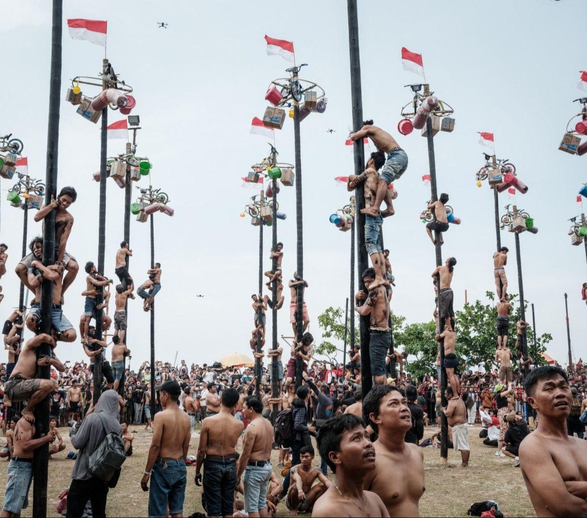 Di samping festival dan pawai budaya, berbagai ajang perlombaan juga diadakan untuk menambah semarak perayaan. Salah satunya lomba panjat pinang yang paling diminati oleh masyarakat. Foto:&nbsp;Yasuyoshi CHIBA / AFP