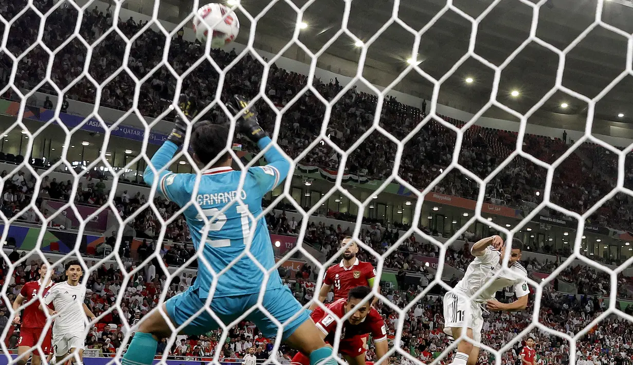 Kiper Timnas Indonesia, Ernando Ari Sutaryadi kebobolan gol ketiga yang dicetak striker Timnas Irak, Aymen Hussein pada laga pertama Grup D Piala Asia 2023 Qatar di Ahmad bin Ali Stadium, Al-Rayyan, Doha, Senin (15/1/2024). (AFP/Karim Jaafar)