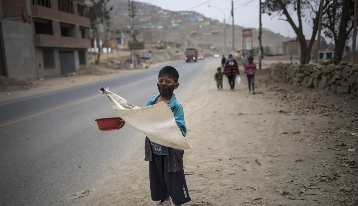 Keyler Martinez, memohon sambil memegang bendera putih yang menandakan kebutuhan mendesak akan makanan selama pandemi virus corona di pinggir jalan di pinggiran kota Lima, Peru (22/8/2020).  (AP Photo/Rodrigo Abd)