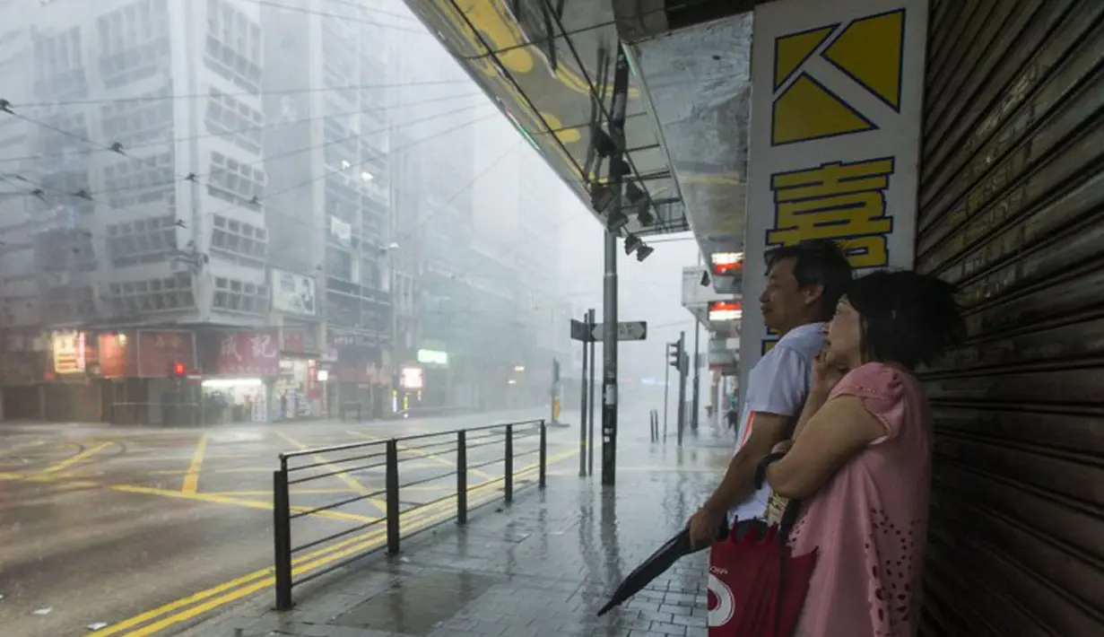 Beberapa warga berteduh menunggu Topan Kalmaegi reda di distrik Sentral Hong Kong, (16/9/2014). Topan Kalmaegi melanda Hong Kong mengakibatkan gangguan pada penerbangan dan memaksa penutupan pasar saham. (AFP PHOTO/Xaume Olleros)