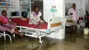 Pasien dan anggota keluarganya berada di dalam bangsal yang tergenang banjir di Nalanda Medical College Hospital, daerah Bihar, India, 29 Juli 2018. Rumah sakit itu digenangi air kotor dengan sejumlah ikan terlihat berenang memenuhi lantai. (AFP PHOTO)