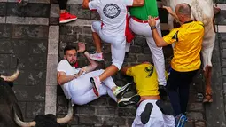 Para pengunjung berlari dan terjatuh di samping banteng-banteng petarung Victoriano del Río selama acara lari banteng ketiga di festival San Fermín di Pamplona, Spanyol, Kamis, 9 Juli 2026. (AP Photo/Miguel Oses)