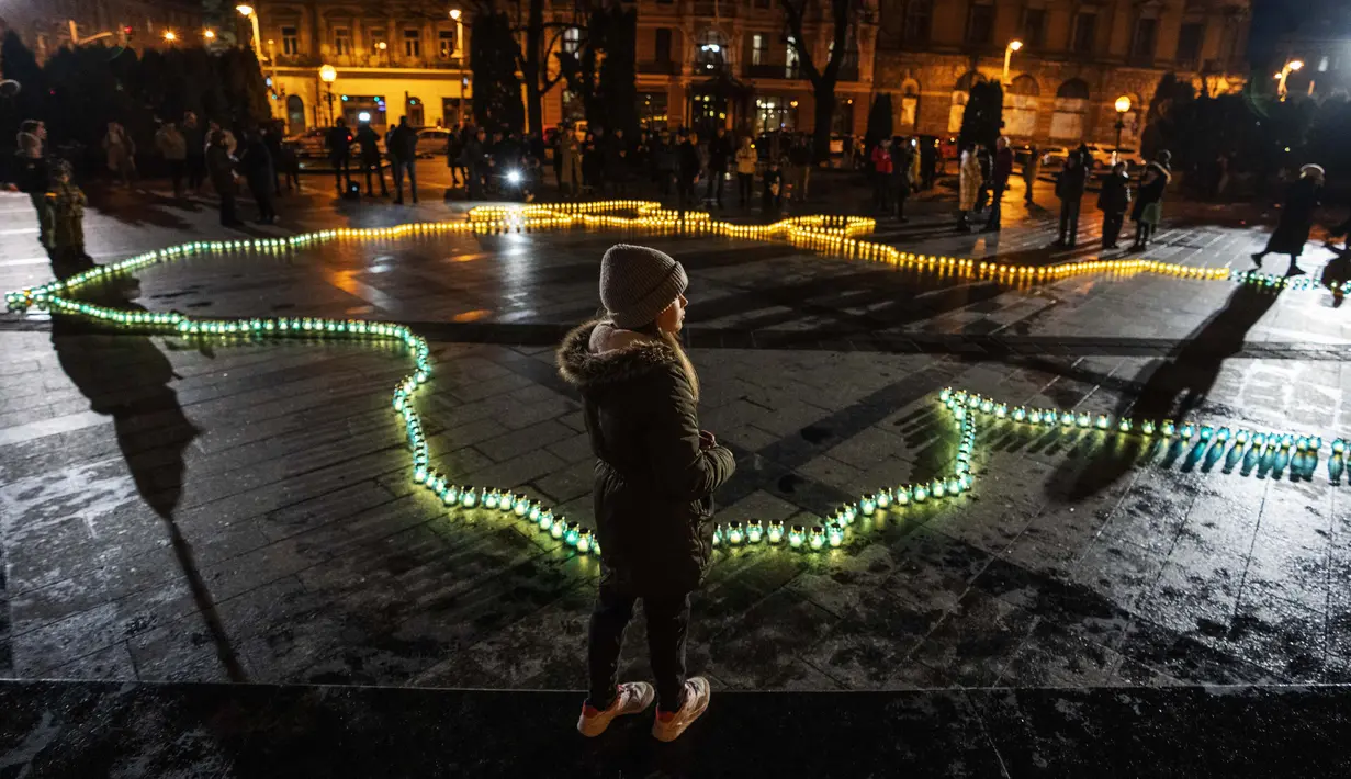 Seorang gadis berdiri di depan lilin yang menyala membentuk peta Ukraina di depan monumen Taras Shevchenko, di Lviv, Ukraina barat, Selasa malam (5/4/2022). Orang-orang Ukraina berkumpul untuk momen menghormati nyawa yang hilang dalam perang. (AP Photo/Nariman El- Mofty)