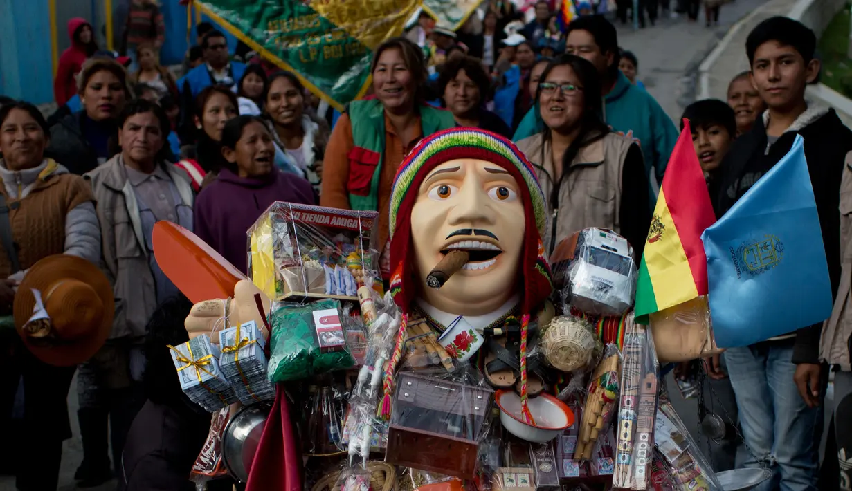 Sejumlah orang berada didekat patung dewa Ekeko yang dipenuhi dengan aneka barang saat arak-arakan di La Paz, Bolivia (23/1). Organisasi PBB, UNESCO mengumumkan Alista merupakan warisan tak berwujud pada Desember 2017. (AP Photo / Juan Karita)