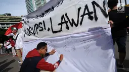 Warga menandatangani spanduk dukungan anti korupsi yang dibentangkan saat Hari Bebas Kendaraan di kawasan Bundaran HI, Jakarta, Minggu (10/12). Aksi dilakukan untuk memperingati Hari Antikorupsi Sedunia, 9 Desember. (Liputan6.com/Helmi Fithriansyah)