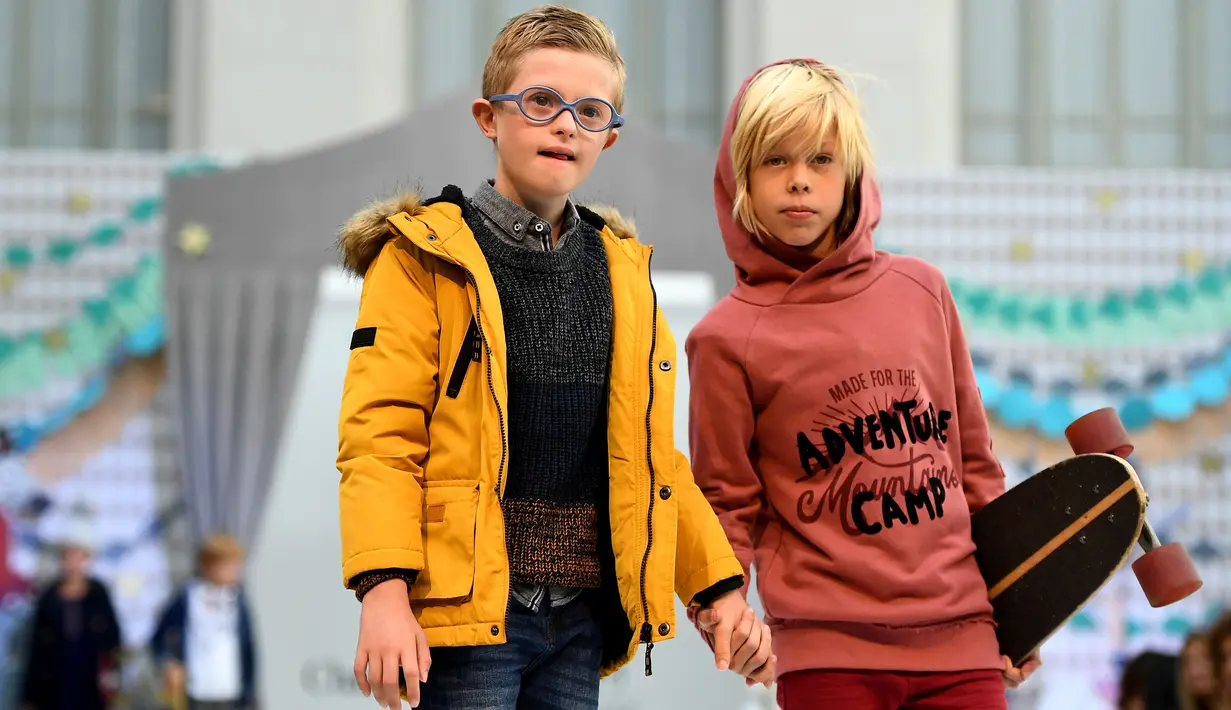 Dua anak yang salah satunya dengan down syndrome berpose saat ambil bagian di atas catwalk pekan mode Petite Fashion Week di Madrid, 6 Oktober 2017. Sejumlah anak berkebutuhan khusus ini tampil bersama dengan model anak-anak lainnya. (GABRIEL BOUYS/AFP)