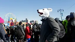 Seorang peserta mengenakan topeng saat menghadiri acara renang Polar Bear Club di Coney Island, New York (1/1). Dalam acara tersebut, para peserta diwajibkan untuk berenang di air yang dingin. (Yana Paskova/Getty Images/AFP)