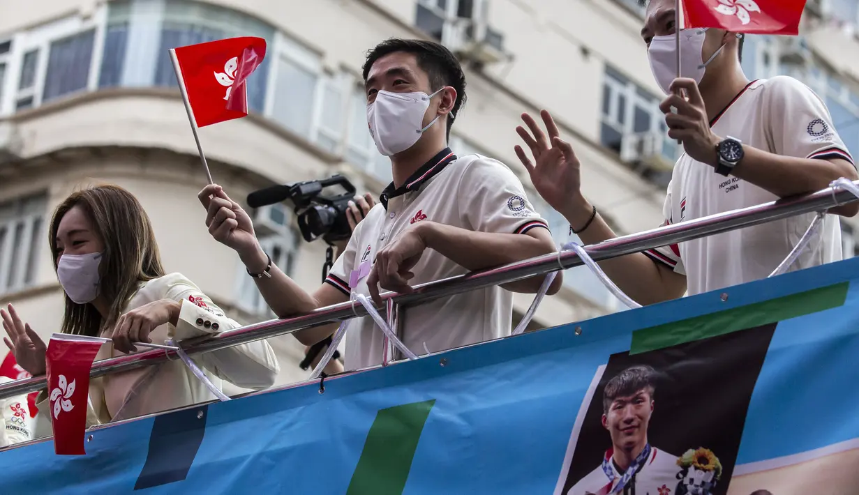 Anggota delegasi Olimpiade Hong Kong mengibarkan bendera selama parade bus, setelah Olimpiade Tokyo 2020, di Hong Kong, Kamis (19/8/2021). Hong Kong yang memiliki 46 atlet perwakilan pada Olimpiade Tokyo 2020 berhasil mengumpulkan satu emas, dua perak dan tiga perunggu. (ISAAC LAWRENCE/AFP)