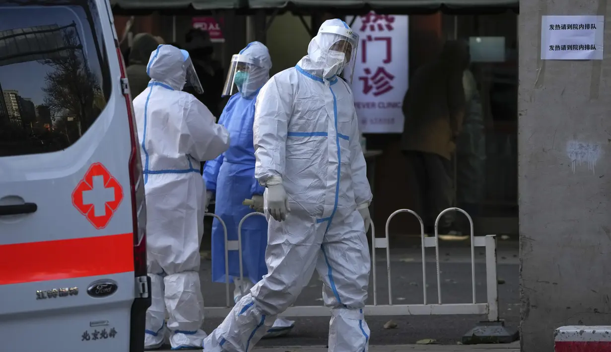 Seorang pekerja ambulans berjalan di dekat petugas medis yang saling mengobrol saat warga menunggu untuk memasuki demam sebuah rumah sakit di Beijing, Selasa (13/12/2022). Beberapa universitas di China mengatakan akan mengizinkan mahasiswanya menyelesaikan semester dari rumah dengan harapan mengurangi potensi wabah COVID-19 yang lebih besar selama kesibukan perjalanan Tahun Baru Imlek di bulan Januari mendatang. (AP Photo/Andy Wong)