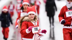 Seorang anak perempuan berpakaian Sinterklas mengambil bagian dalam Santa Claus Run di Pristina, Minggu (16/12). Ratusan pelari berpartisipasi dalam lomba lari amal untuk menggalang dana bagi keluarga yang membutuhkan di Kosovo. (Armend NIMANI/AFP)