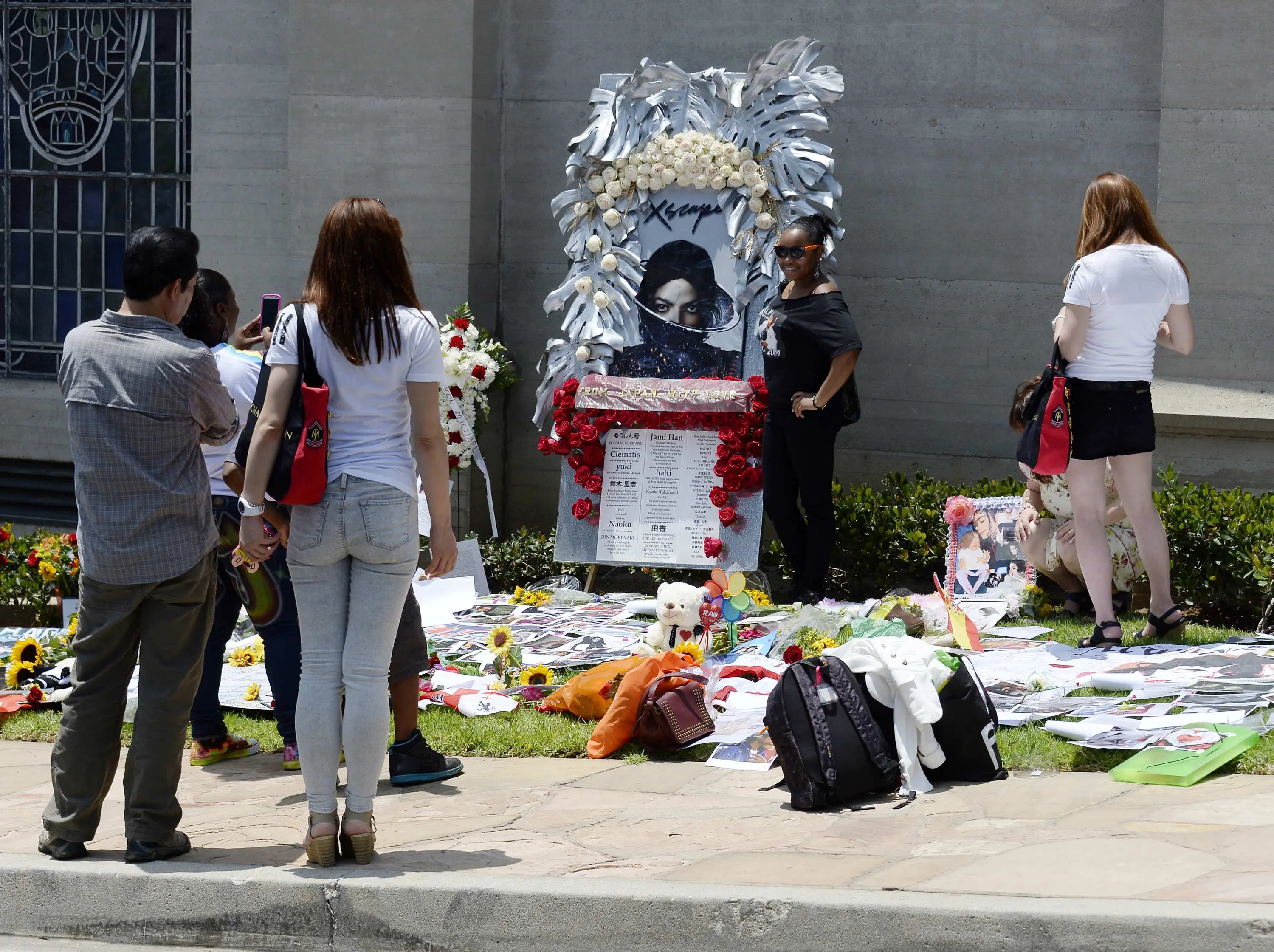 	Seorang fans berpose dengan foto Michael Jackson di depan pintu masuk makam di mana Jackson dikebumikan di Forest Lawn Memorial Park-Glendale, California, Rabu (25/6/14). (REUTERS/Kevork Djansezian)
