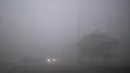 Sebuah mobil dengan lampu depan melaju melewati jalan yang diselimuti kabut tebal pada pagi yang dingin di pinggiran New Delhi, India (1/1/2021). Di sisi lain, Madhya Pradesh di India tengah mendapat kelegaan dari dingin yang menggigit karena merkuri naik beberapa tingkat. (AP Photo/Altaf Qadri)