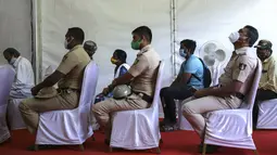Polisi India menunggu bersama orang lain untuk menerima vaksin COVID-19 dosis ketiga di pusat vaksinasi di Bengaluru, India (10/1/2022). Penyebaran varian Omicron yang cepat telah memicu lonjakan kasus baru hingga delapan kali lipat sejak awal tahun. (AP Photo/Aijaz Rahi)