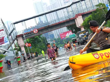 Seorang petugas polisi menggunakan perahu karet untuk melewati banjir yang menggenangi kawasan Grogol, Jakarta Barat, Rabu (11/2/2015). (Liputan6.com/Faisal R Syam)