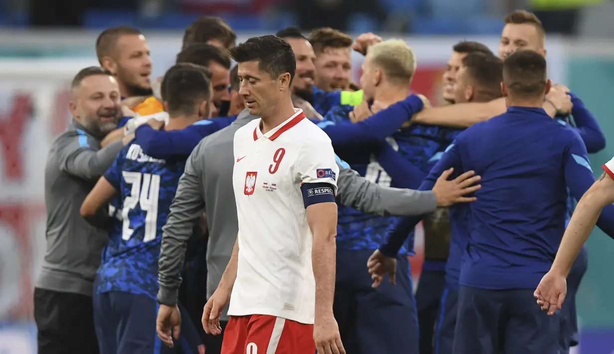 Striker Polandia, Robert Lewandowski (tengah) berjalan saat para pemain Slovakia merayakan kemenangan usai pertandingan grup E Euro 2020 di stadion Saint Petersburg di St. Petersburg, Rusia, Senin (14/6/2021).  Slovakia menang tipis atas Polandia 2-1. (Kirill Kudryavtsev/Pool via AP)