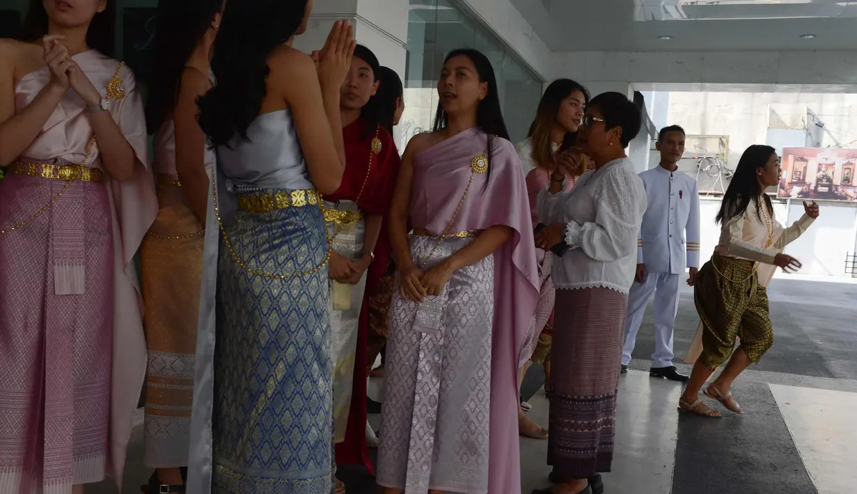 Para pekerja wanita mengenakan kostum tradisional berjalan bersiap mengikuti upacara keagamaan Buddha sebagai persiapan festival tahun baru Songkran di luar kantor di Bangkok, Thailand (9/4). (AFP Photo/Romeo Gacad)