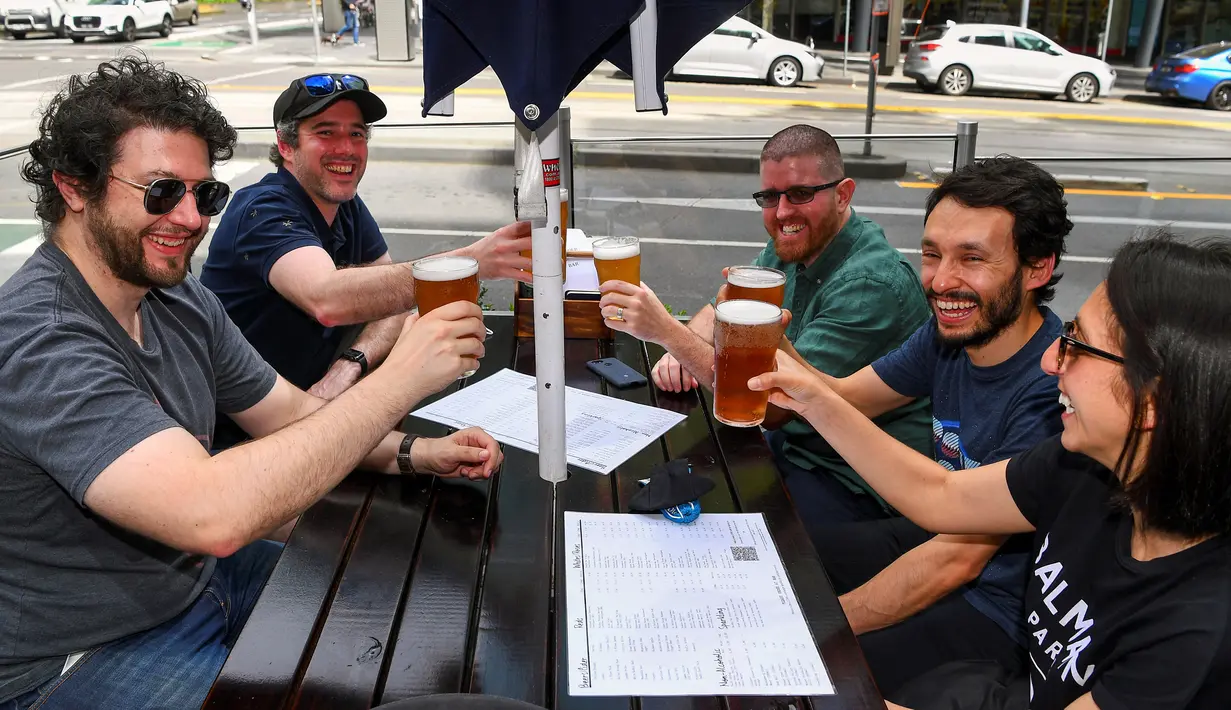 Pelanggan menikmati bir di sebuah pub di Melbourne, Australia, Jumat (22/10/2021). Kota terbesar kedua di Australia ini kembali dibuka setelah mengalami salah satu rangkaian lockdown pandemi yang paling lama di dunia. (William WEST/AFP)