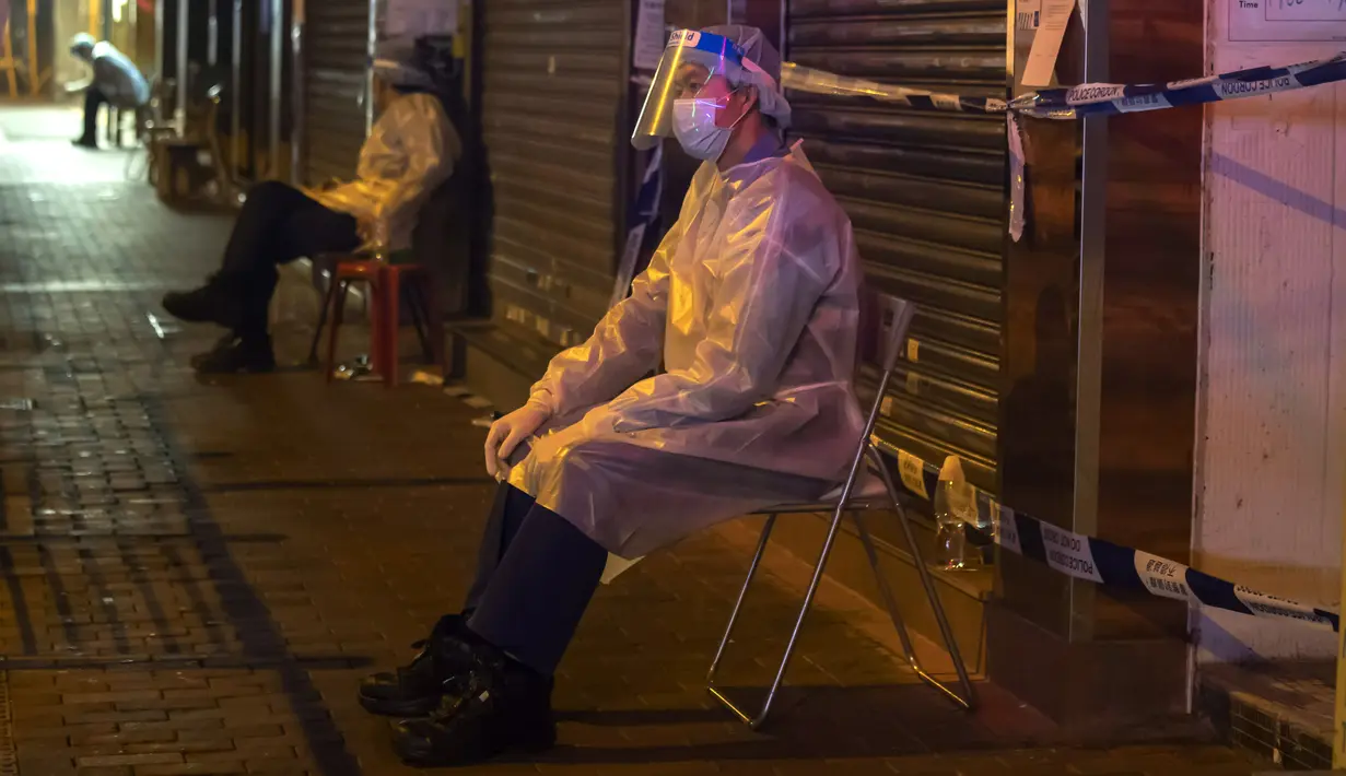 Petugas kesehatan mengenakan APD berjaga di area tertutup di distrik Jordan, di Hong Kong, Minggu (24/1/2021). Ribuan warga Hong Kong diperintahkan tetap tinggal di rumah setelah otoritas setempat memberlakukan lockdown untuk pertama kalinya sejak pandemi COVID-19 merebak. (AP Photo/ Kin Cheung)
