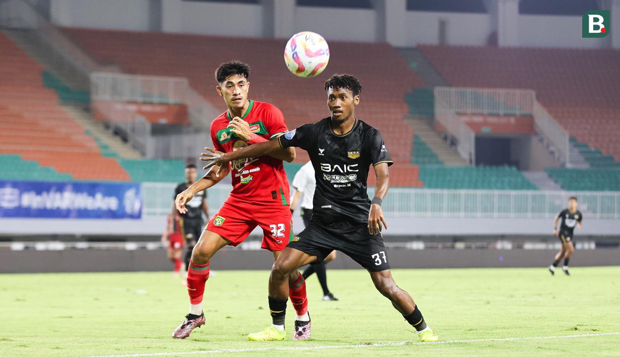 Pemain Dewa United, Alta Balah (kanan) sedang bersebut bola dengan pemain Persebaya Surabaya Riswan Lauhin dalam pertandingan Dewa United melawan Persebaya Surabaya pada pekan ke-24 BRI Liga 1 di Stadion Pakansari, Kabupaten Bogor, Jumat (21/2/2025) malam WIB. (Bola.com/Abdul Aziz)