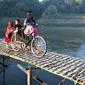 Seorang ibu mengantar anaknya ke sekolah melewati jembatan bambu di atas Sungai Bengawan Solo, Jateng. Hari ini merupakan hari pertama masuk sekolah untuk tahun ajaran baru.(Antara)