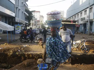 Seorang perempuan menjual makanan di sebuah jalan di Conakry, Guinea, Rabu (8/9/2021). Para pemimpin militer baru Guinea berusaha mempererat cengkeraman mereka pada kekuasaan setelah menggulingkan Presiden Alpha Conde. (AP Photo/Minggu Alamba)