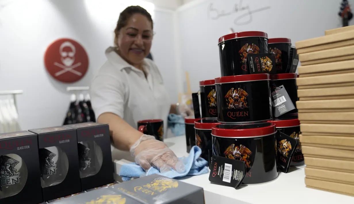 Pekerja membersihkan rak di toko baru yang didedikasikan untuk menjual merchandise resmi band rock Queen sebelum dibuka di London, Senin (27/9/2021). Band legendaris Queen membuka toko pop-up di Carnaby Street pada pekan ini untuk menandai lima dekade mereka di kancah musik (AP Photo/Alastair Grant)